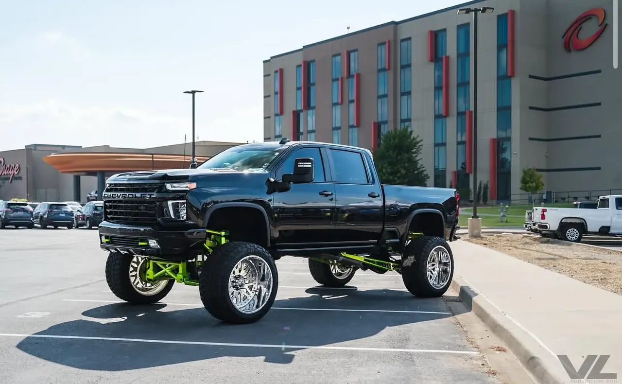 Lifted black Chevrolet Silverado 2500HD with lime green powdercoated suspension on forged wheels